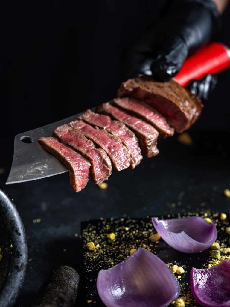 בשר יפיפה חתוך מוצג על סכין שף